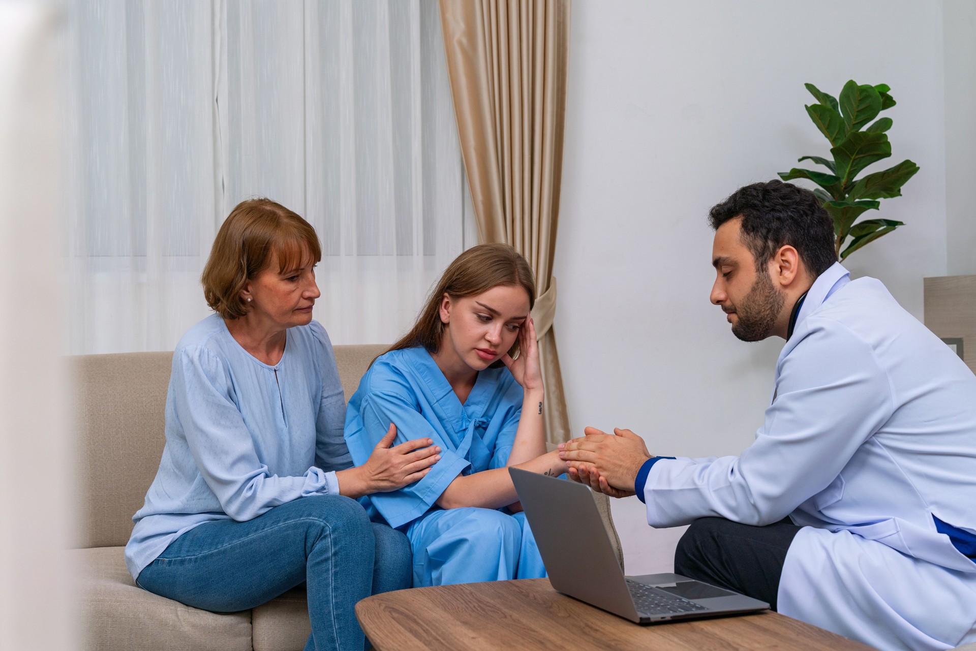 Doctor discussing medical condition with a female patient and her mother using a computer laptop