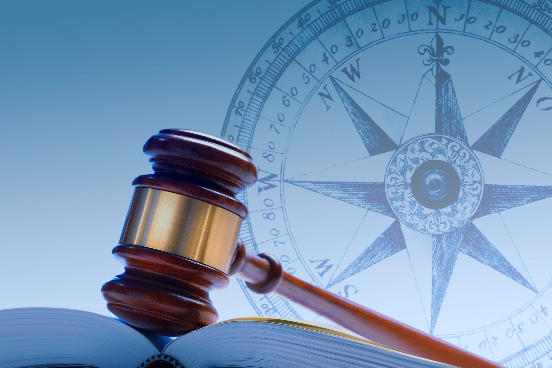 Gavel Resting In Open Law Book With Compass In The Background